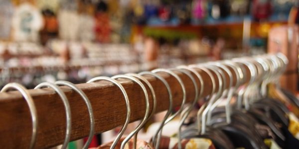 wooden-clothes-racks-with-hangers-and-with-colorful-clothes-on-a-blurred-background-inside-a-shop_t20_lorNGb